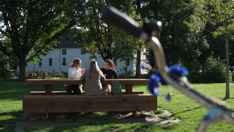 Three students sitting outside in front of the castle of Hotel School Maastricht