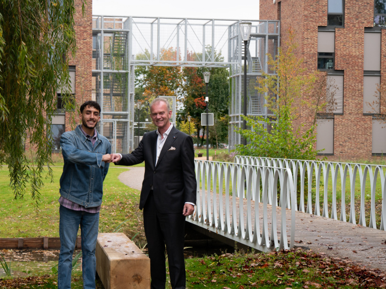Jean Maroun en directeur Ad smits bij de bank, bij de kanjel met op de achtergrond het Campus gebouw