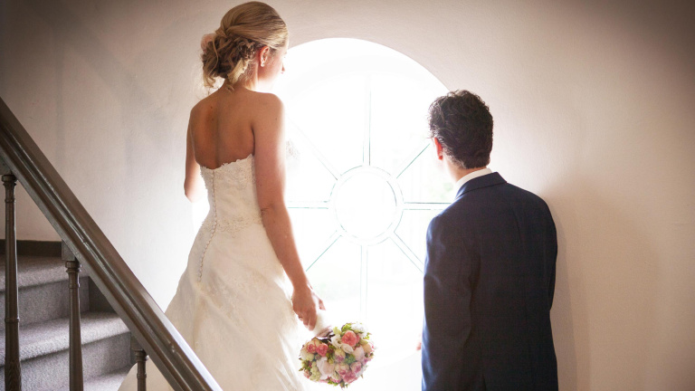 Studente staat achter bar in Le Coin en legt de laatste hand aan een rode cocktail door een schijfje limoen toe te voegen.