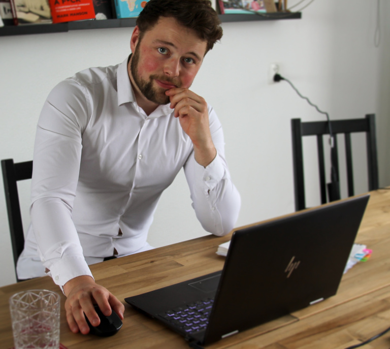 Young man, white shirt, beard, laptop, desk