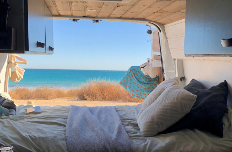 Een bed in een busje met uitzicht op de zee