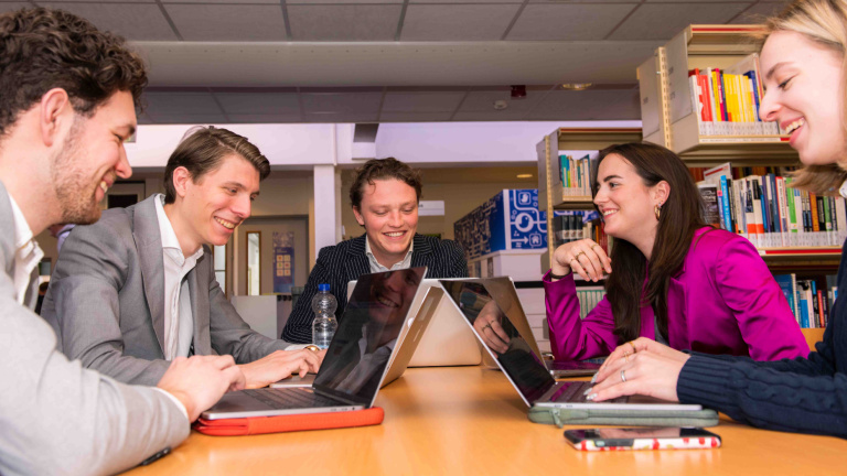 Drie studenten bespreken hun project in de binnentuin van Hotelschool Maastricht.