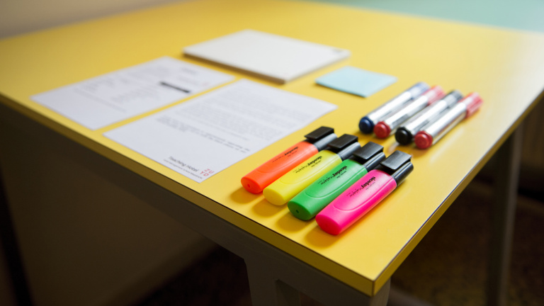 Studente staat achter bar in Le Coin en legt de laatste hand aan een rode cocktail door een schijfje limoen toe te voegen.