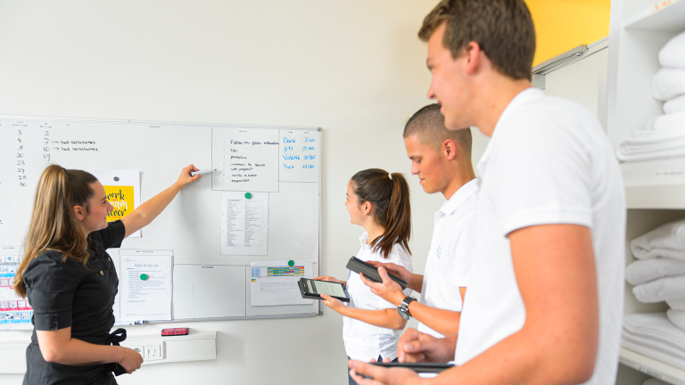 Drie eerstejaars studenten krijgen instructie voor de housekeeping in het Teaching Hotel